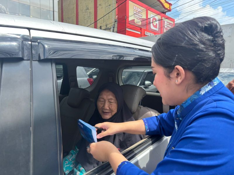 Petugas teller BRI kanca Cimanggis, Ainaya Lana Arista H melayani nasabah pensiunan dengan memberikan pendampingan administrasi di dalam kendaraan (Foto Istimewa) 